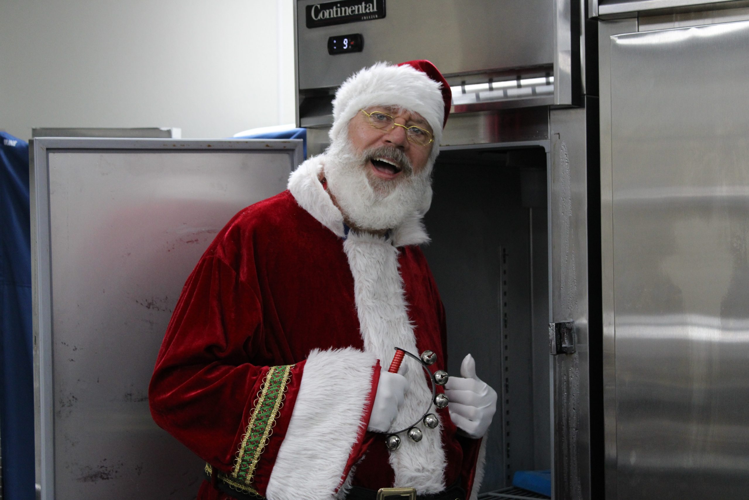 Santa standing near a freezer.